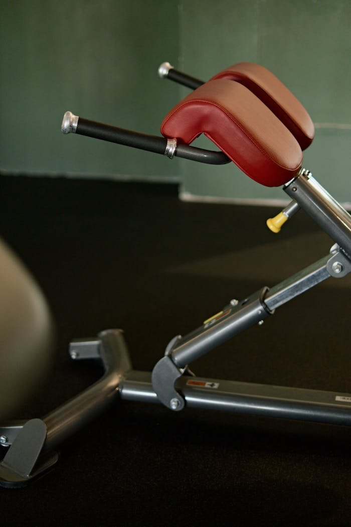 Close-up image of gym hyperextension equipment with red padded support in a fitness center.