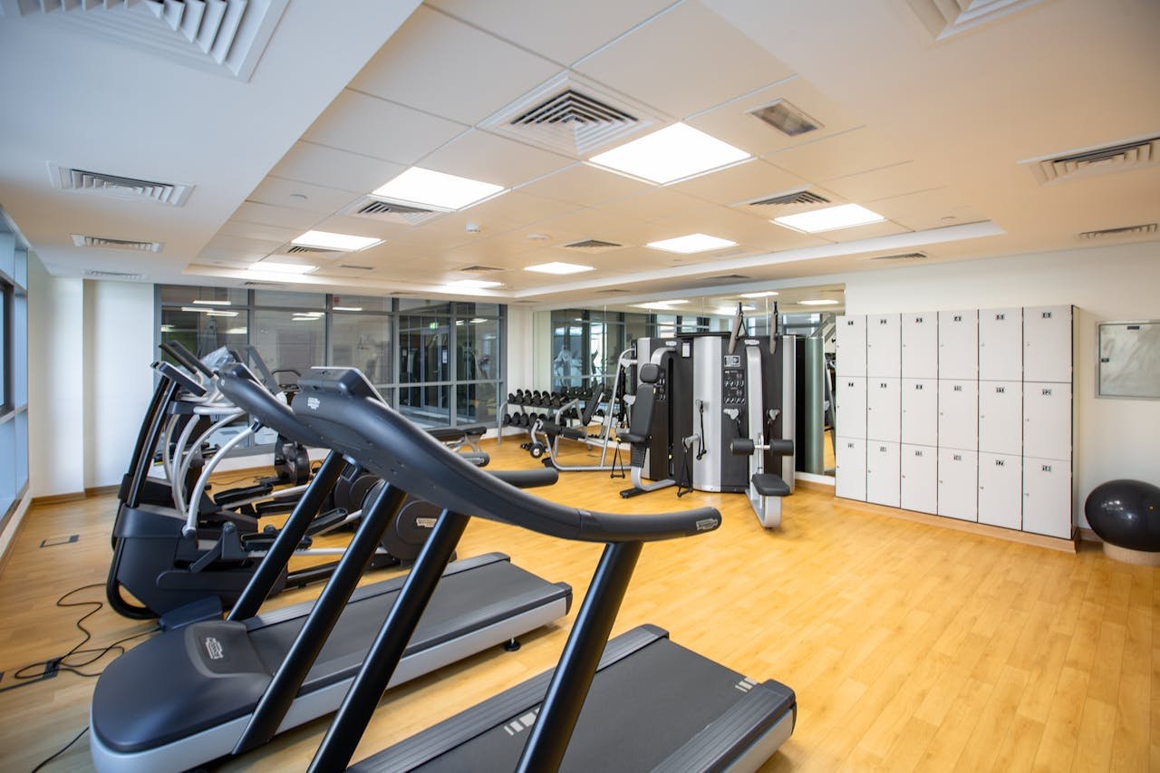About Spacious gym interior featuring treadmills, fitness machines, lockers.